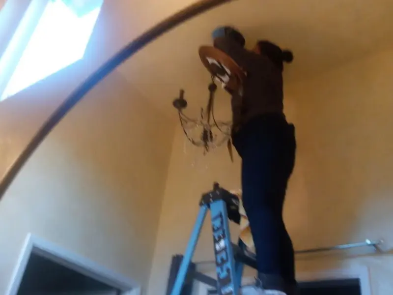 Electrician installing a chandelier in a Bullhead City residence
